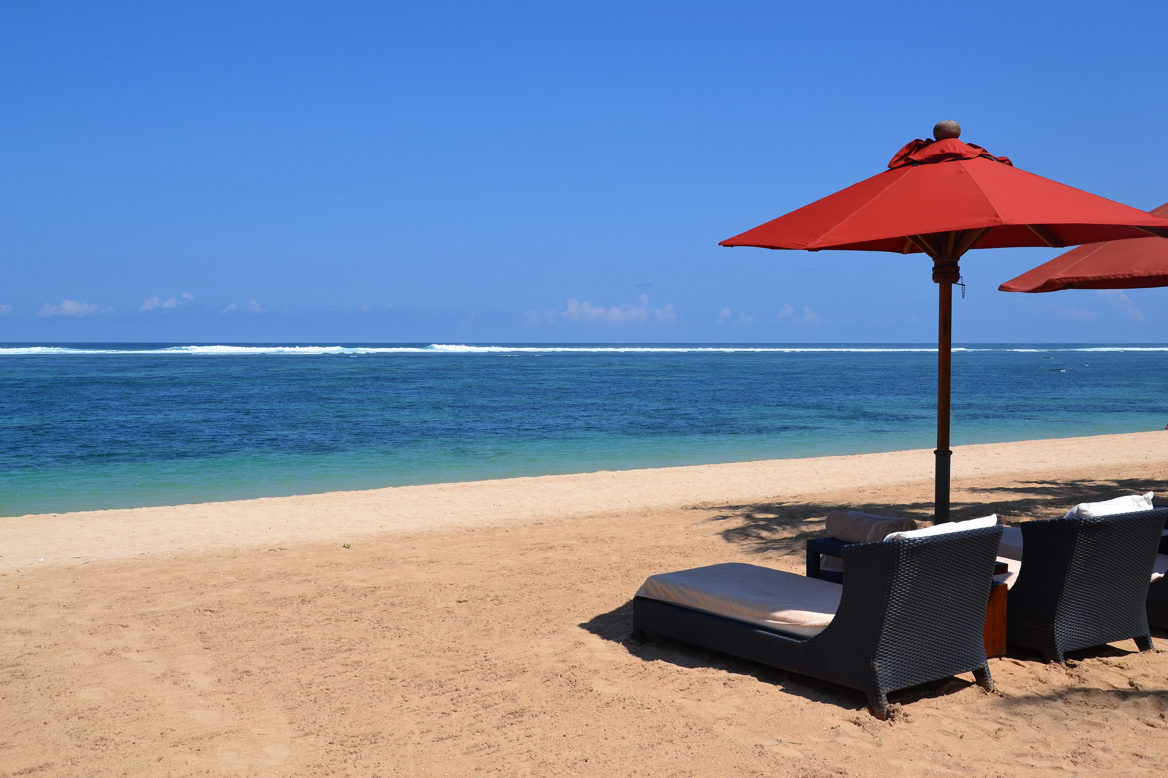 St. Regis Nusa Dua hoolitsetud rand, Bali — palmipuud, rannalavatsid ja türkiissinine vesi.