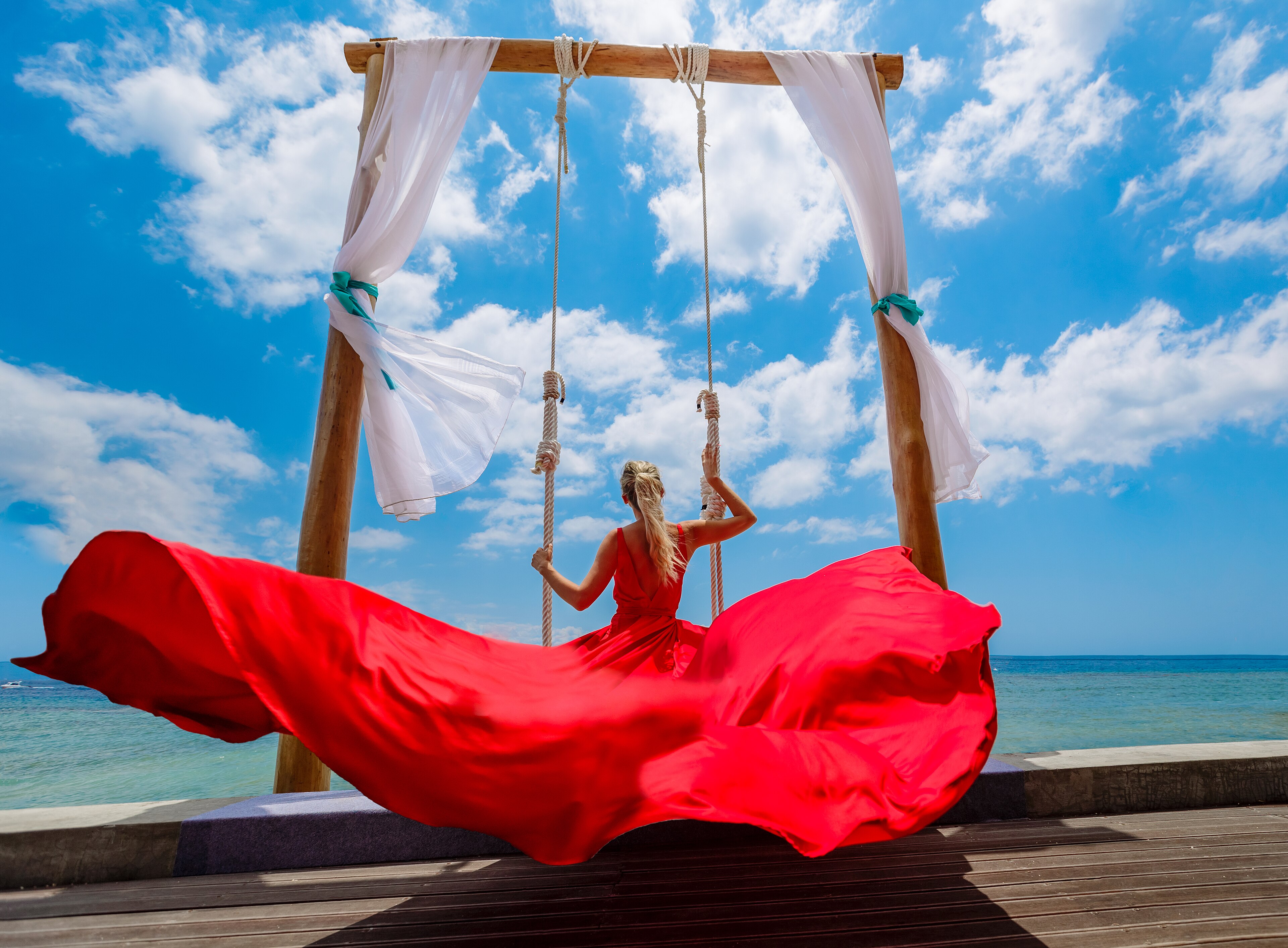 Puust kiik The Osh Bali Beach Clubis kalju ja türkiissinise mere taustal.