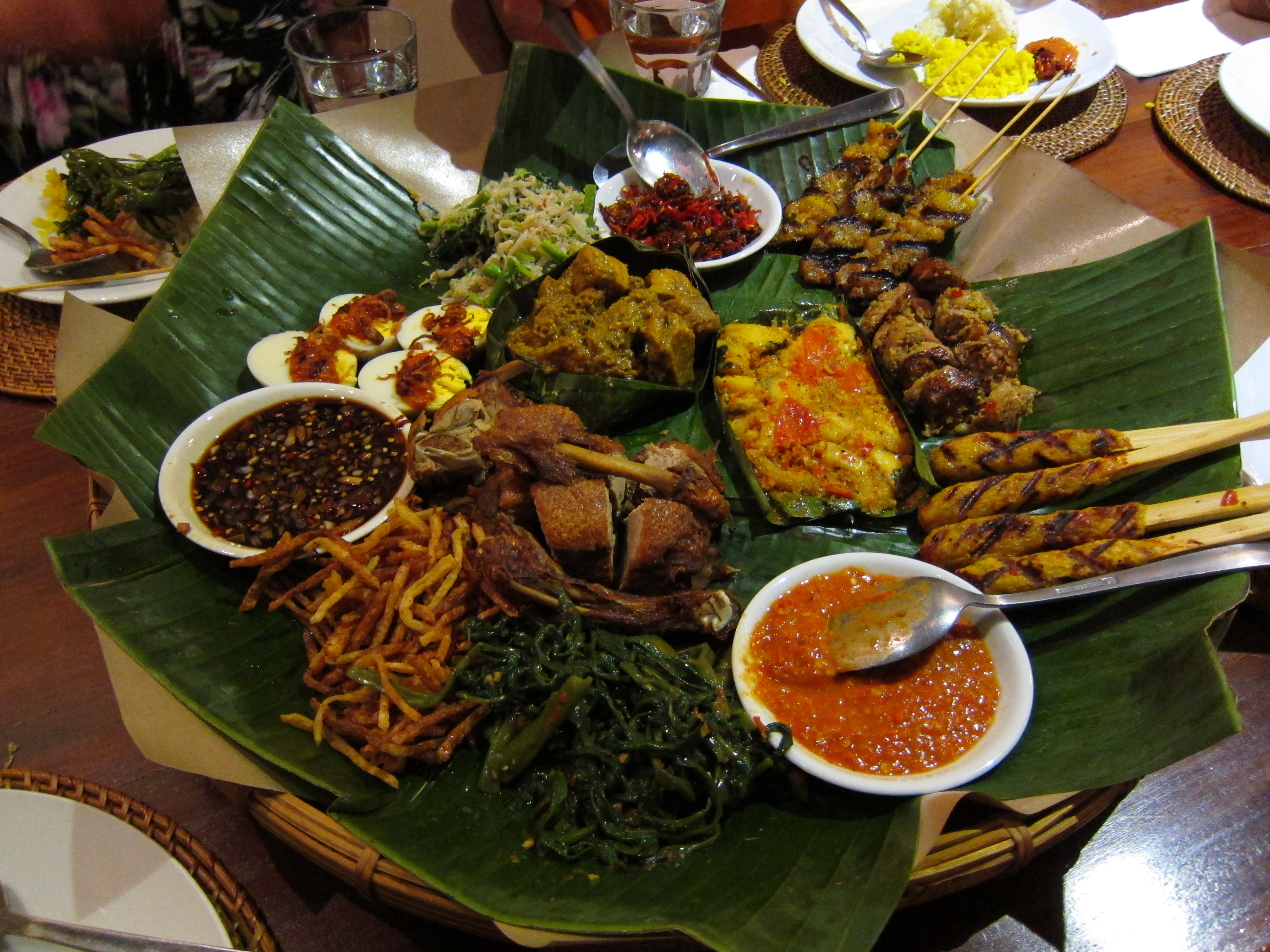 Traditsiooniline Bali roogade kogum puulaual — satay, sambal, riis ja köögiviljad.